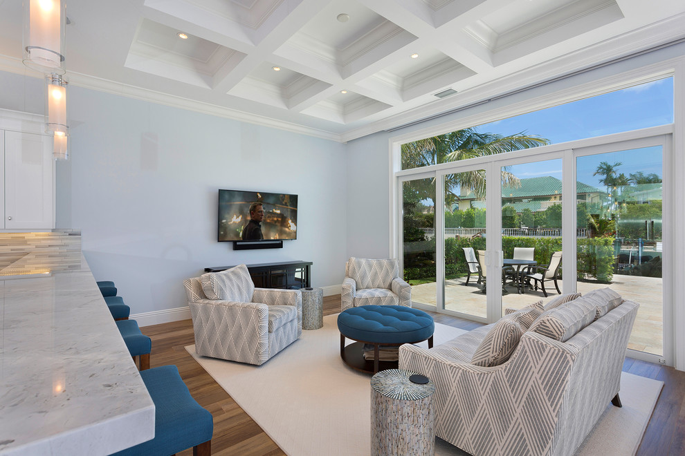 This is an example of an expansive tropical formal open concept living room in Other with medium hardwood floors, no fireplace, a wall-mounted tv, brown floor and grey walls.