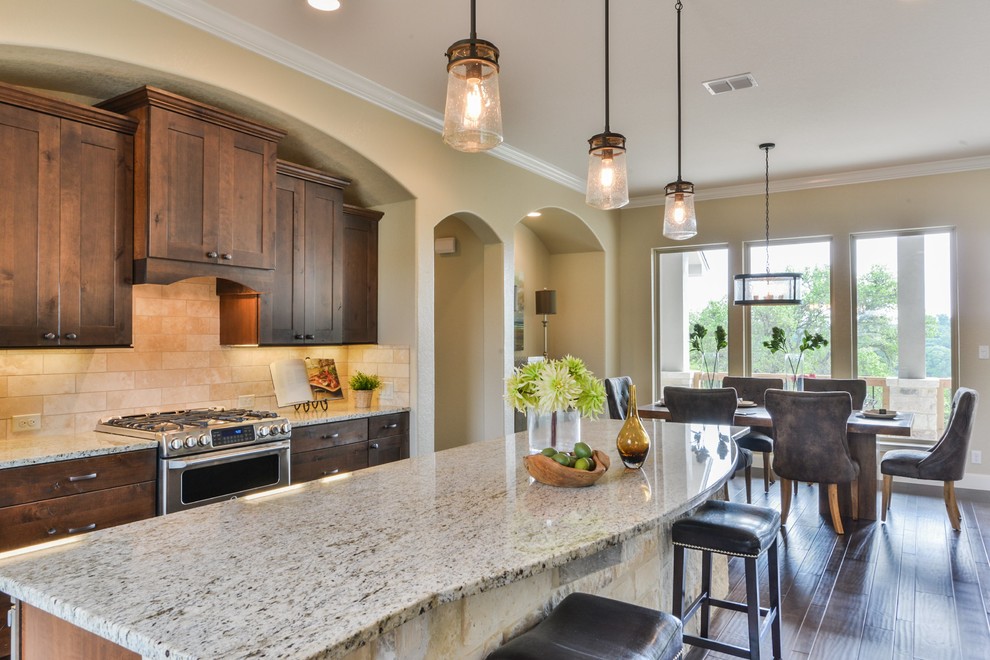 Example of a large mountain style l-shaped dark wood floor and brown floor open concept kitchen design in Austin with shaker cabinets, dark wood cabinets, granite countertops, beige backsplash, ceramic backsplash, stainless steel appliances and an island