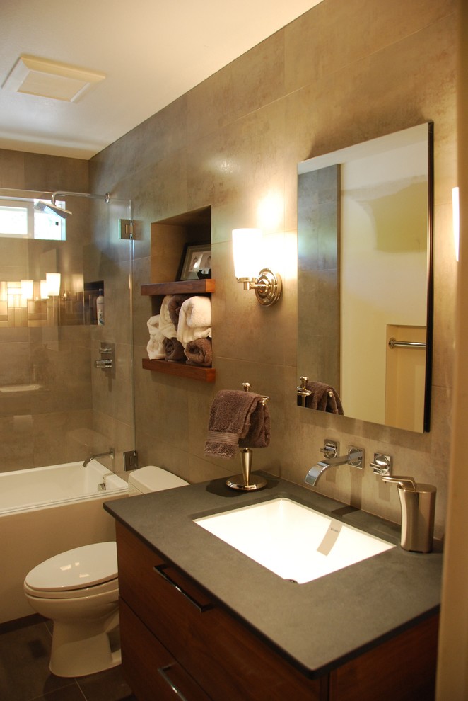 Photo of a small contemporary kids bathroom in San Francisco with flat-panel cabinets, dark wood cabinets, an alcove tub, a shower/bathtub combo, gray tile, ceramic tile, grey walls, ceramic floors, an undermount sink, soapstone benchtops, brown floor and a hinged shower door.