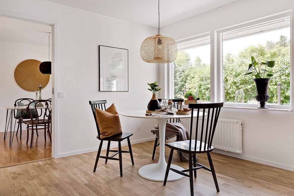 This is an example of a contemporary dining room in Stockholm with white walls, no fireplace, medium hardwood floors and brown floor.
