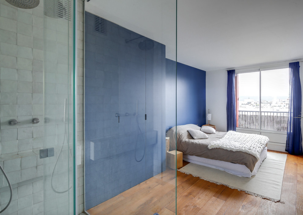 Exemple d'une grande chambre parentale tendance avec un mur bleu, un sol en bois brun, aucune cheminée et un sol marron.