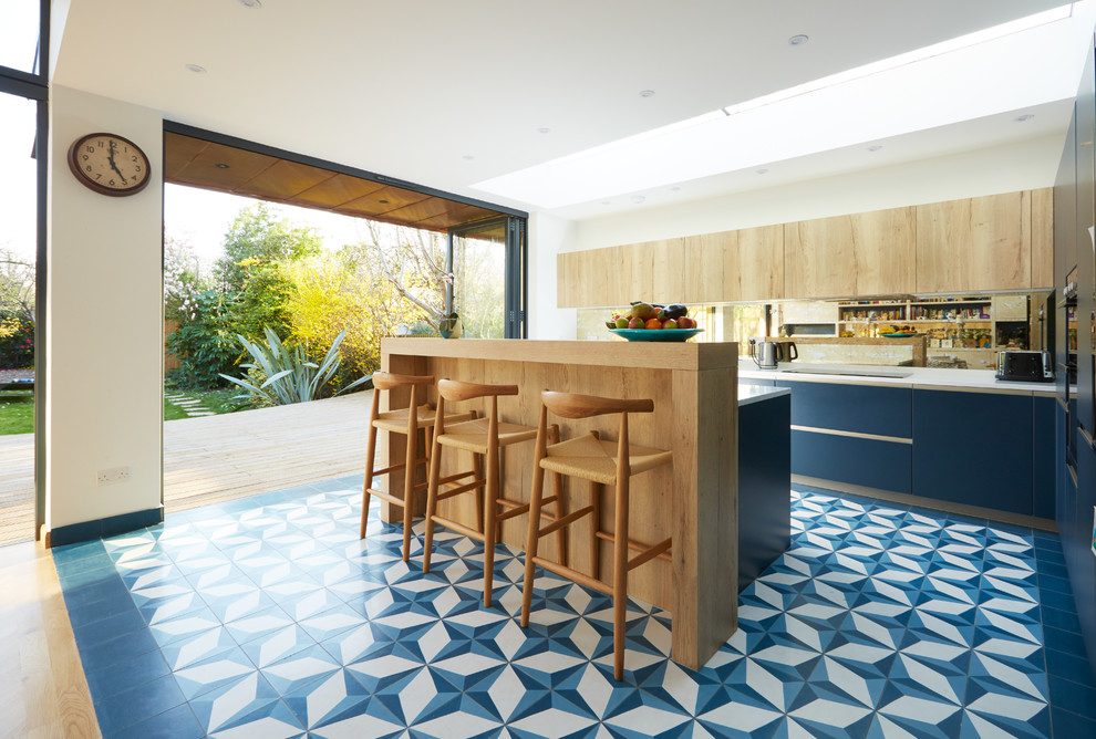 Mid-sized modern l-shaped kitchen in London with flat-panel cabinets, blue cabinets, with island and multi-coloured floor.