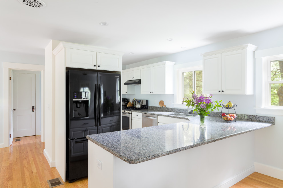 Inspiration for a mid-sized traditional l-shaped eat-in kitchen in Boston with an undermount sink, raised-panel cabinets, white cabinets, granite benchtops, stainless steel appliances, light hardwood floors, a peninsula and grey benchtop.