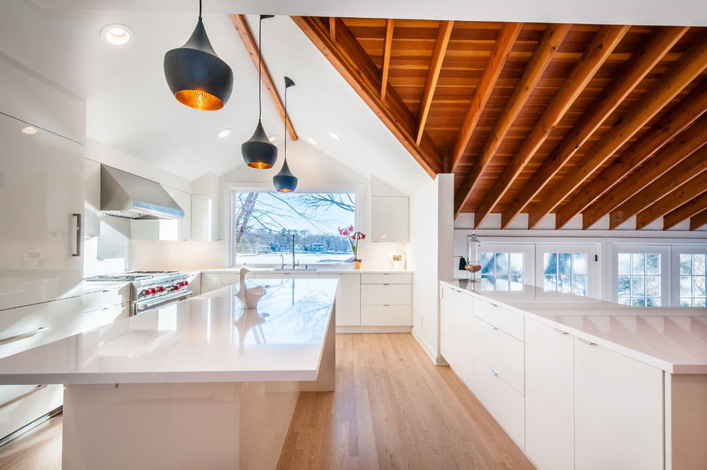 This is an example of a mid-sized modern u-shaped eat-in kitchen in Other with an undermount sink, flat-panel cabinets, white cabinets, quartz benchtops, white splashback, porcelain splashback, panelled appliances, light hardwood floors, with island and brown floor.