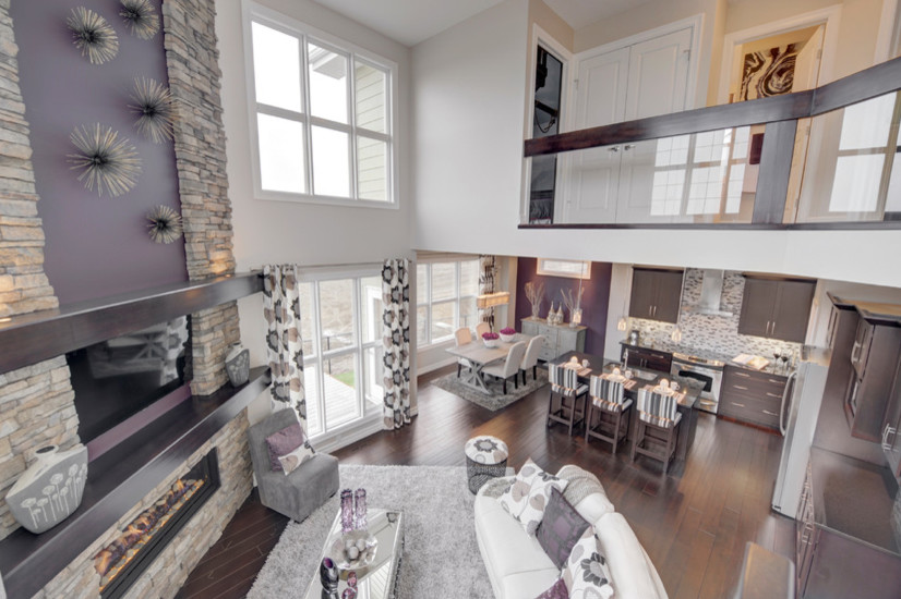 Design ideas for a large transitional open concept living room in Edmonton with grey walls, dark hardwood floors, a standard fireplace, a stone fireplace surround and a wall-mounted tv.