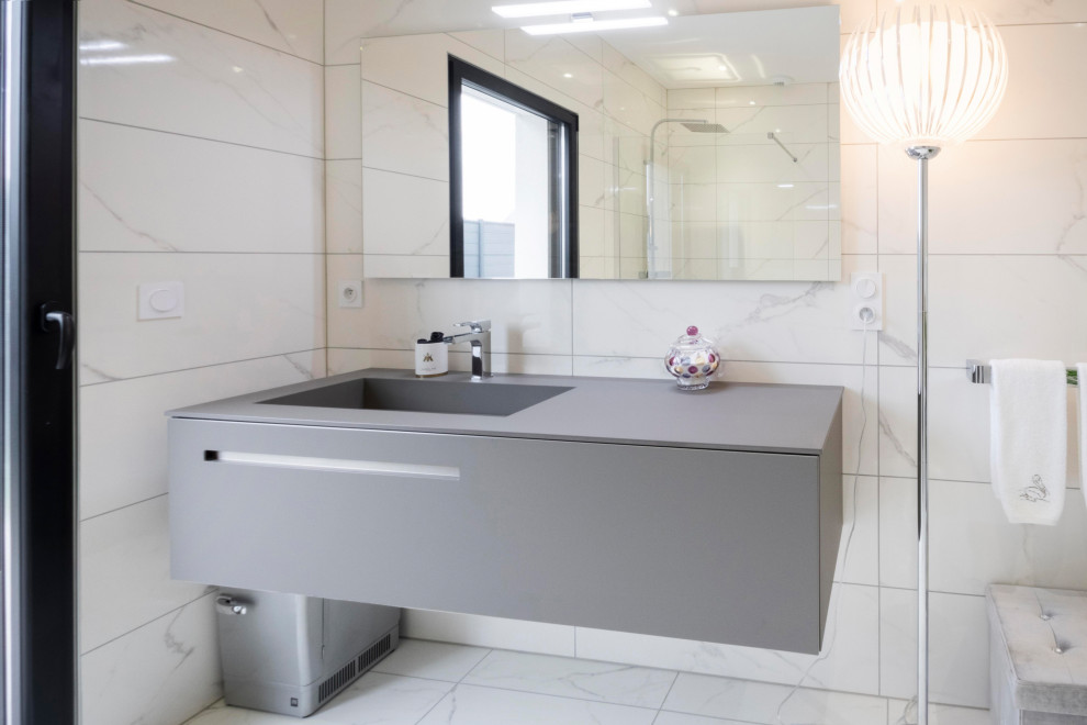 Photo of a mid-sized modern master bathroom in Rennes with flat-panel cabinets, an undermount tub, a curbless shower, a wall-mount toilet, marble, marble floors, solid surface benchtops, a single vanity, a floating vanity, beige cabinets, a trough sink and beige benchtops.