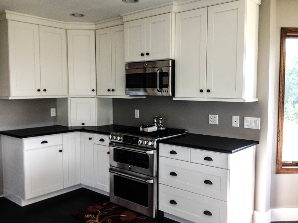 Large transitional l-shaped dark wood floor and black floor open concept kitchen photo with a farmhouse sink, shaker cabinets, white cabinets, quartz countertops, stainless steel appliances and an island