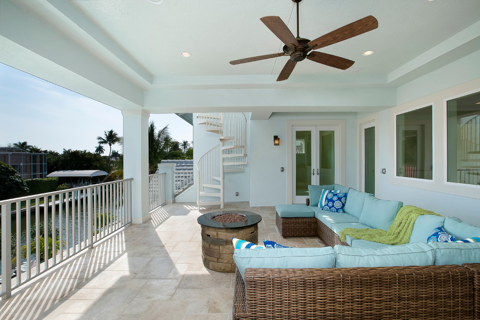 Photo of a mid-sized tropical balcony in Miami with a fire feature and a roof extension.