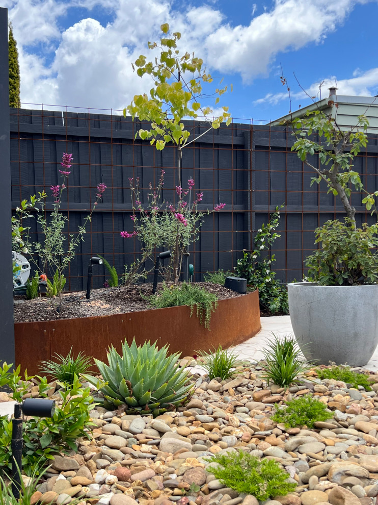 Immagine di un piccolo giardino vittoriano esposto in pieno sole dietro casa in estate con un ingresso o sentiero, pavimentazioni in pietra naturale e recinzione in metallo