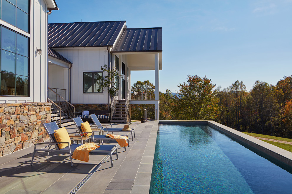 Modelo de piscina infinita campestre de tamaño medio rectangular en patio trasero con adoquines de piedra natural