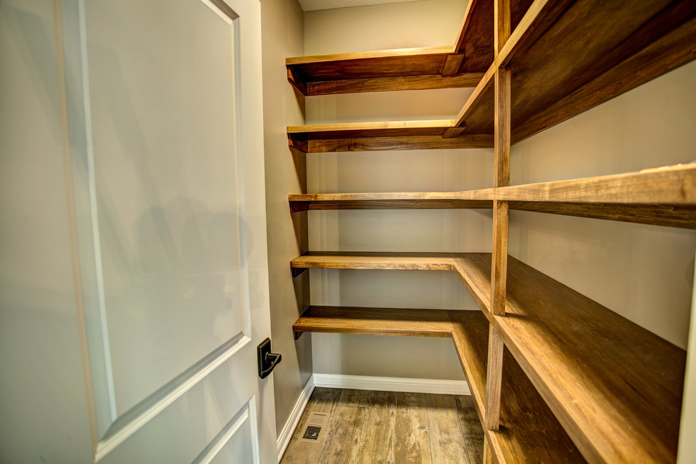 Kitchen pantry - mid-sized transitional single-wall medium tone wood floor and gray floor kitchen pantry idea with an undermount sink, raised-panel cabinets, dark wood cabinets, granite countertops, metallic backsplash, metal backsplash, stainless steel appliances and an island