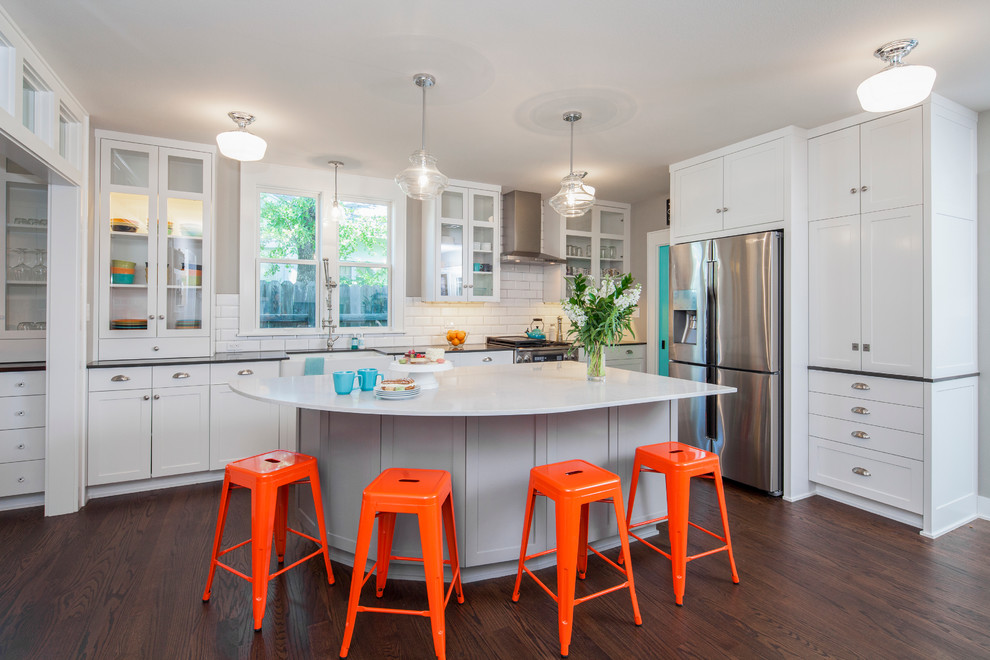 Mid-sized transitional l-shaped kitchen in Austin with a farmhouse sink, recessed-panel cabinets, white cabinets, quartz benchtops, white splashback, stainless steel appliances, dark hardwood floors, with island and subway tile splashback.