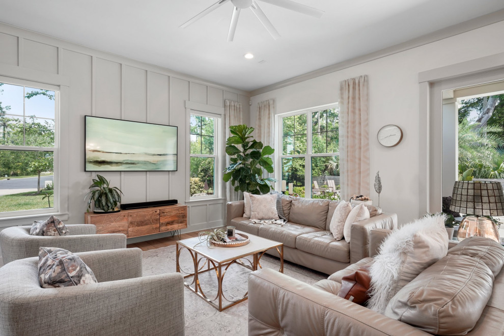 Foto di un grande soggiorno country aperto con pareti bianche, pavimento in legno massello medio e TV a parete