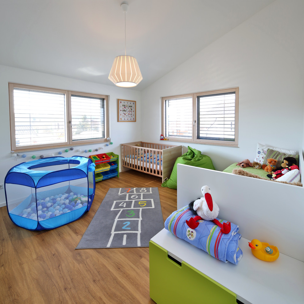 Photo of a mid-sized contemporary nursery for boys in Munich with white walls, medium hardwood floors and brown floor.
