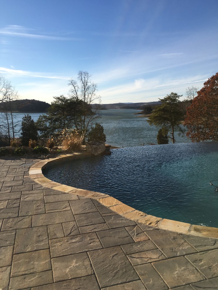 Photo of a large country backyard custom-shaped infinity pool in Other with a hot tub and concrete pavers.