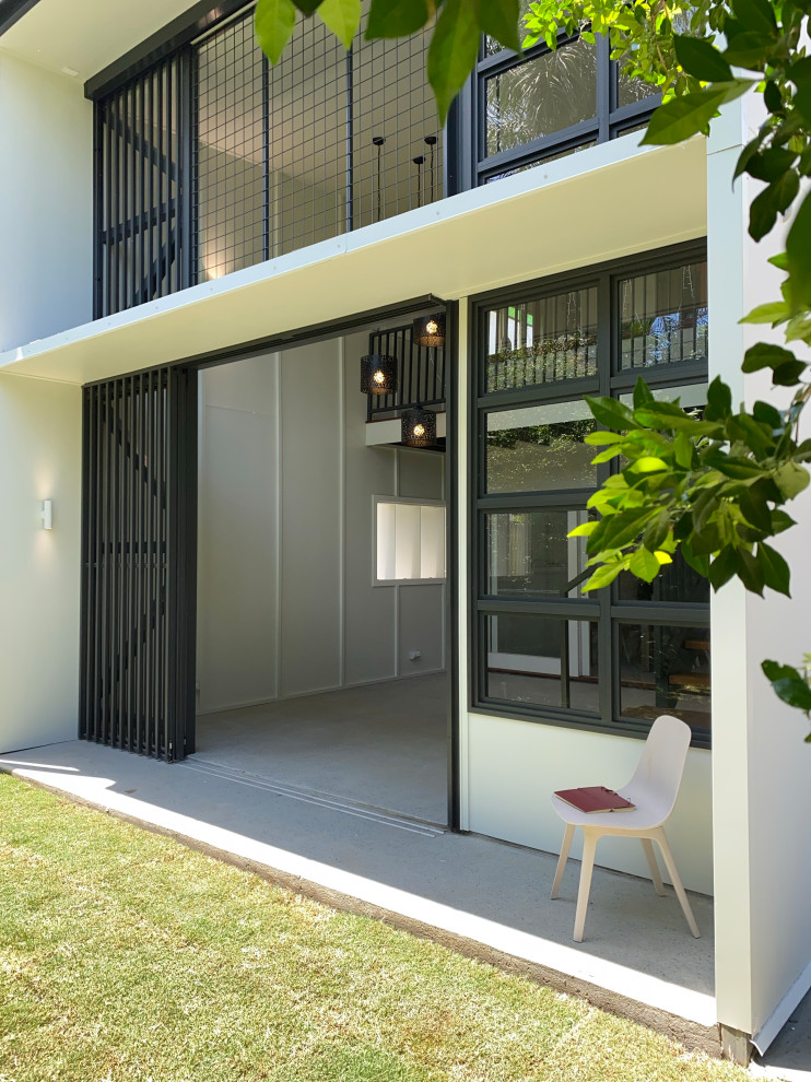 This is an example of a medium sized and white contemporary two floor detached house in Brisbane with concrete fibreboard cladding and board and batten cladding.