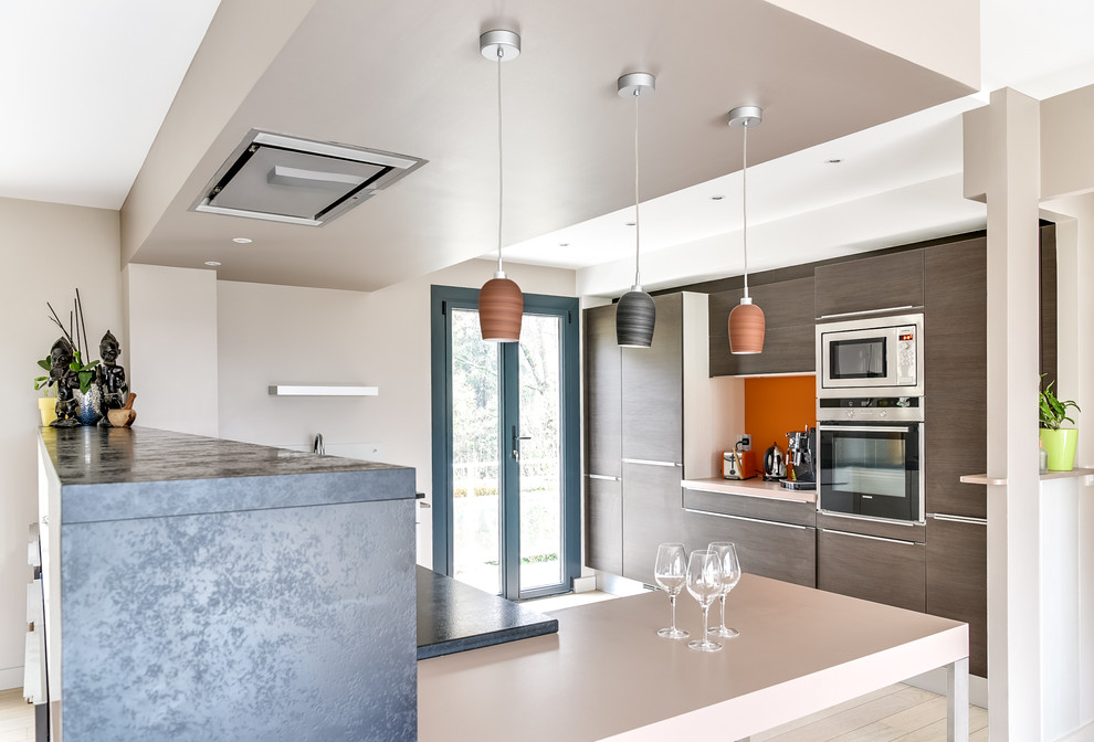 Inspiration for a large modern l-shaped eat-in kitchen in Lyon with flat-panel cabinets, medium wood cabinets, granite benchtops, a peninsula, an undermount sink, orange splashback, timber splashback, stainless steel appliances, light hardwood floors, beige floor and grey benchtop.