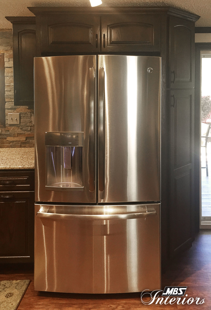 Small transitional u-shaped medium tone wood floor enclosed kitchen photo with an undermount sink, dark wood cabinets, gray backsplash, stone tile backsplash, stainless steel appliances and no island