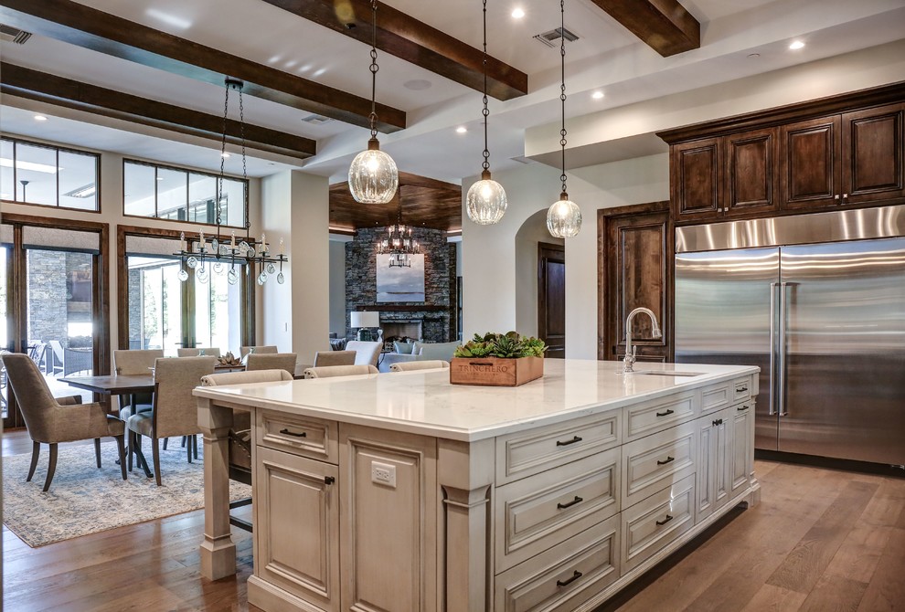 Photo of a large contemporary u-shaped eat-in kitchen in Phoenix with a drop-in sink, raised-panel cabinets, dark wood cabinets, quartz benchtops, white splashback, ceramic splashback, stainless steel appliances, light hardwood floors, with island, brown floor and white benchtop.