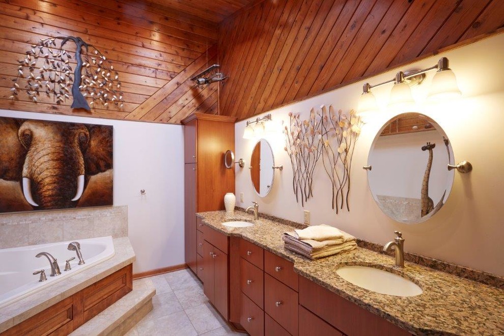 Large traditional bathroom in Other with flat-panel cabinets, medium wood cabinets, a drop-in tub, beige tile, black tile, brown tile, stone tile, white walls, porcelain floors, an undermount sink and granite benchtops.