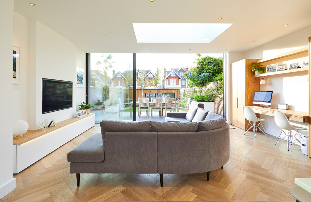Design ideas for a mid-sized contemporary open concept living room in London with white walls, medium hardwood floors, a wall-mounted tv and brown floor.