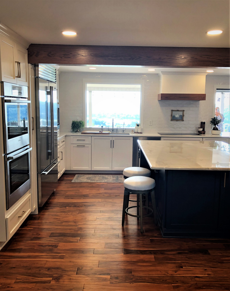 Kitchen pantry - mid-sized transitional l-shaped medium tone wood floor and brown floor kitchen pantry idea with an undermount sink, flat-panel cabinets, blue cabinets, quartz countertops, white backsplash, subway tile backsplash, stainless steel appliances, an island and gray countertops