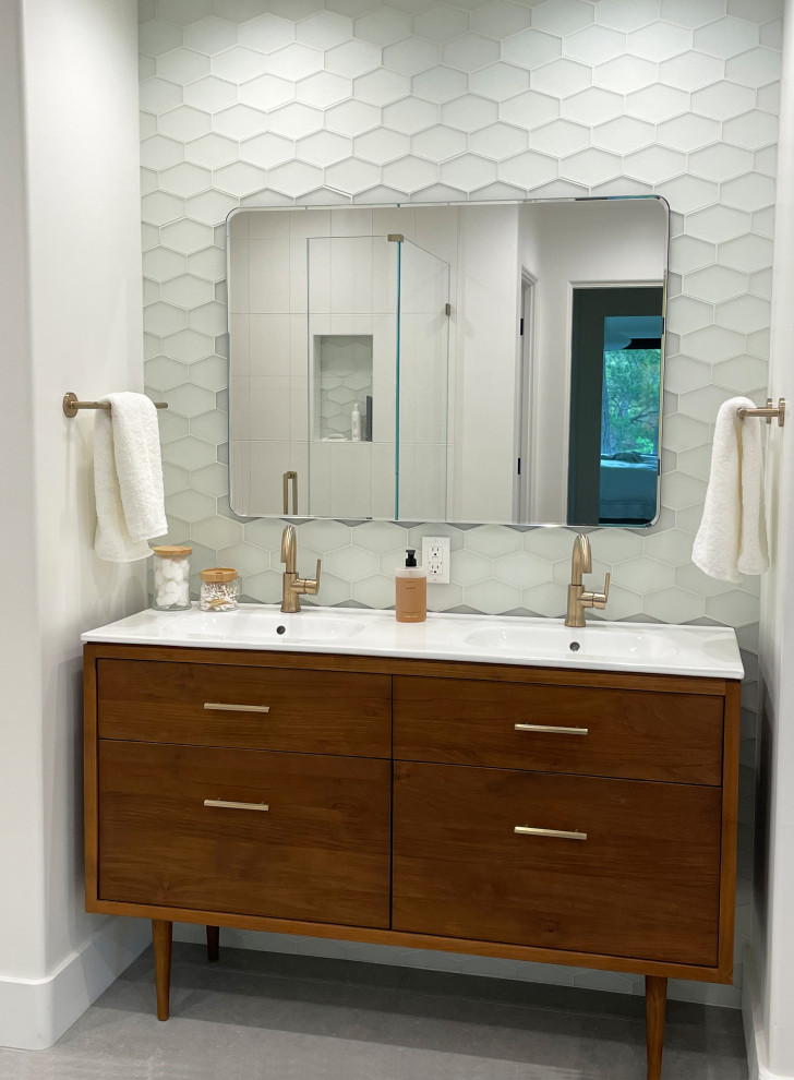 Mid-sized midcentury master bathroom in Nashville with flat-panel cabinets, medium wood cabinets, a one-piece toilet, white tile, glass tile, white walls, porcelain floors, an integrated sink, solid surface benchtops, grey floor, white benchtops, a niche, a double vanity and a freestanding vanity.
