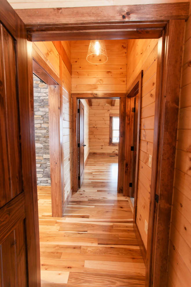 Example of a mountain style light wood floor, yellow floor, wood ceiling and wood wall hallway design