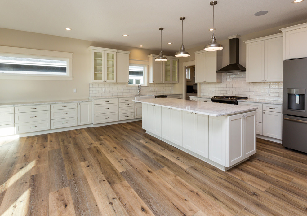 Country l-shaped eat-in kitchen in Other with a farmhouse sink, shaker cabinets, white cabinets, quartz benchtops, white splashback, ceramic splashback, stainless steel appliances, vinyl floors, with island and grey floor.