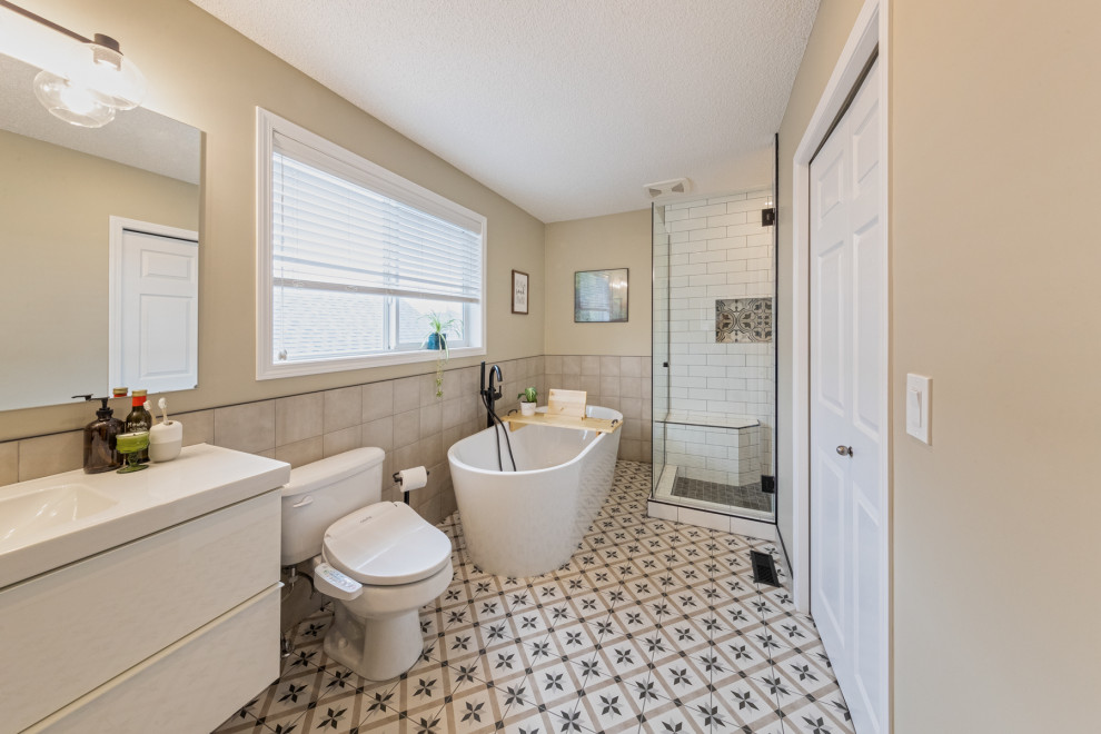 Design ideas for a mid-sized contemporary master bathroom in Edmonton with flat-panel cabinets, white cabinets, a floating vanity, a freestanding tub, a corner shower, a bidet, beige tile, ceramic tile, beige walls, ceramic floors, an integrated sink, laminate benchtops, multi-coloured floor, a hinged shower door, white benchtops, a shower seat and a single vanity.
