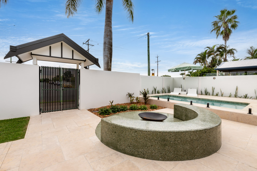 Kleiner Retro Garten im Innenhof im Sommer mit Feuerstelle, direkter Sonneneinstrahlung, Natursteinplatten und Metallzaun in Brisbane