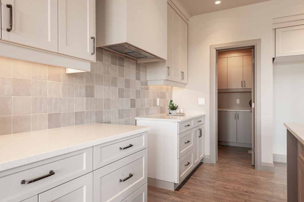 Open concept kitchen - small transitional galley laminate floor and brown floor open concept kitchen idea in Toronto with a double-bowl sink, recessed-panel cabinets, beige cabinets, quartz countertops, beige backsplash, porcelain backsplash, stainless steel appliances, an island and white countertops