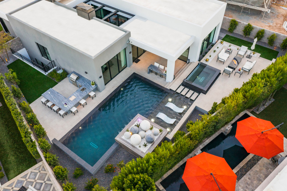 Foto di una piscina a sfioro infinito moderna rettangolare di medie dimensioni e dietro casa con paesaggistica bordo piscina e piastrelle