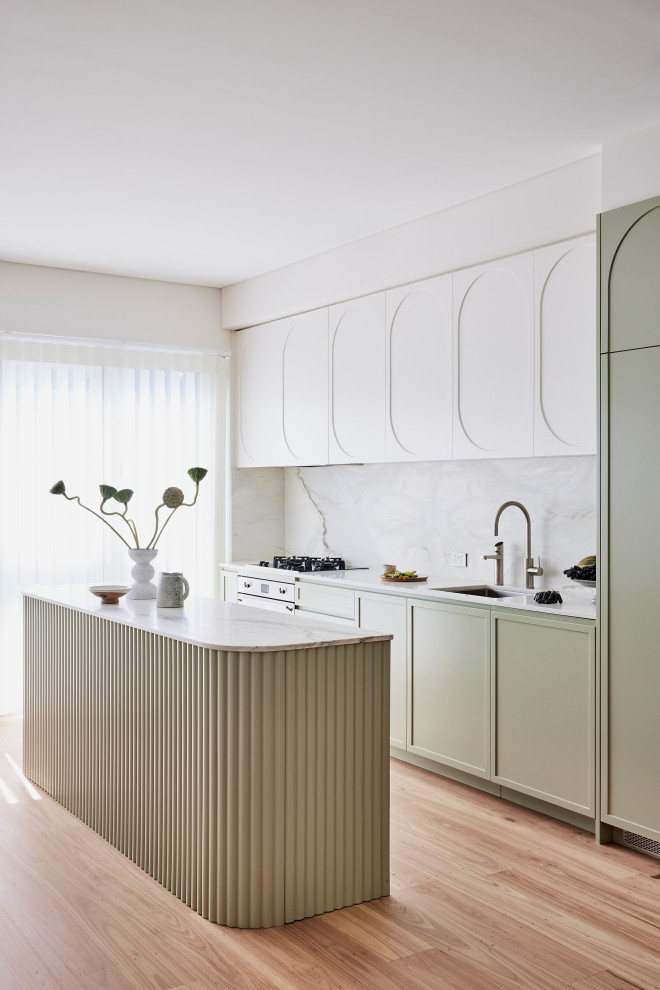 Modern inredning av ett mellanstort grå grått kök, med en undermonterad diskho, skåp i shakerstil, gröna skåp, marmorbänkskiva, grått stänkskydd, stänkskydd i marmor, rostfria vitvaror, ljust trägolv, en köksö och brunt golv