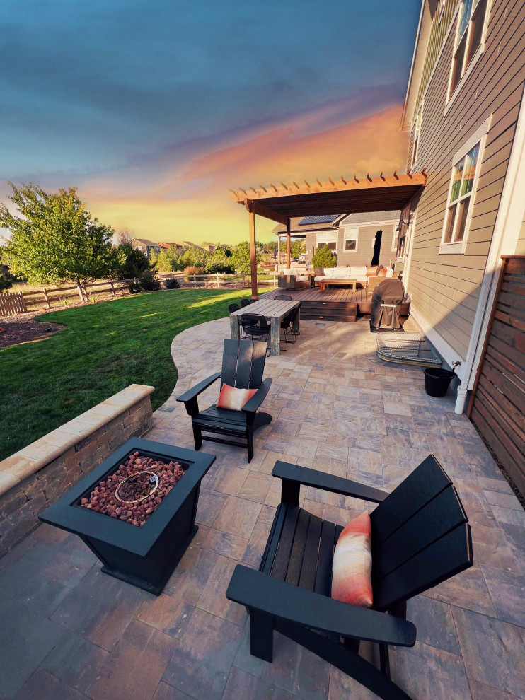 Mid-sized contemporary backyard patio in Denver with a fire feature, natural stone pavers and a pergola.