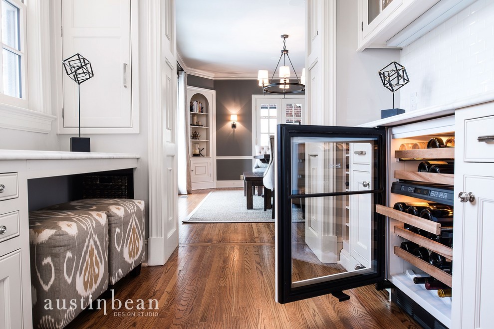 Transitional medium tone wood floor eat-in kitchen photo with a farmhouse sink, glass-front cabinets, white cabinets, marble countertops, white backsplash, subway tile backsplash, stainless steel appliances and gray walls