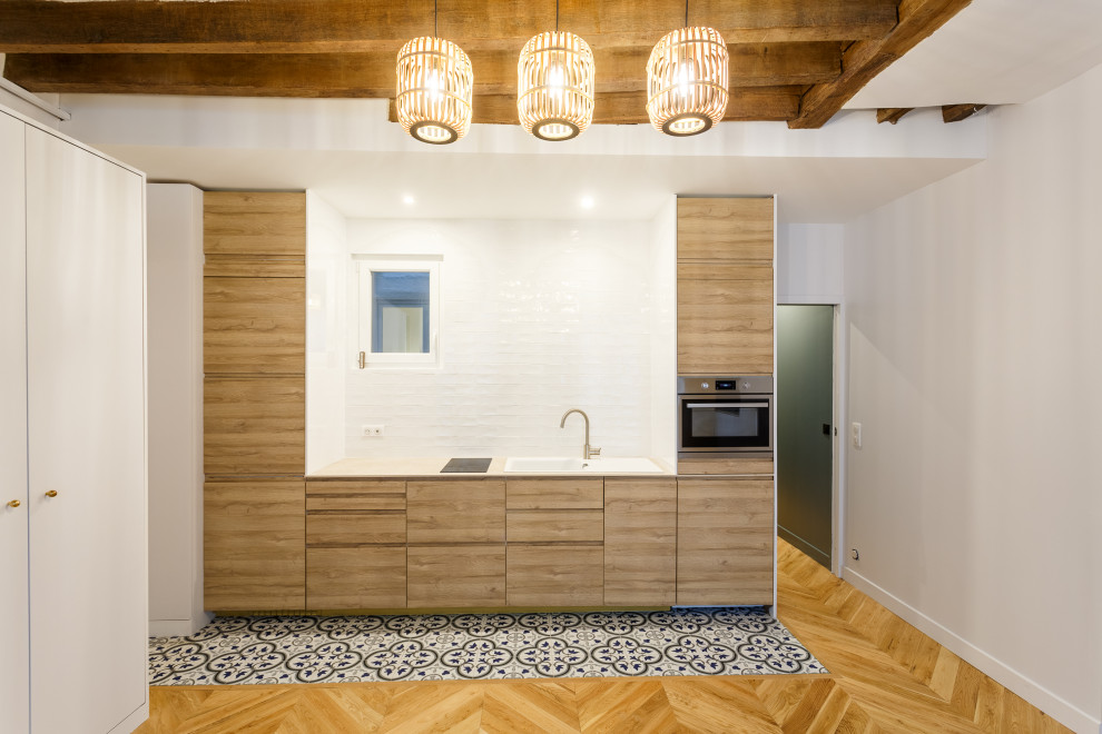 Foto på ett mellanstort beige linjärt kök, med en undermonterad diskho, vitt stänkskydd, rostfria vitvaror och blått golv