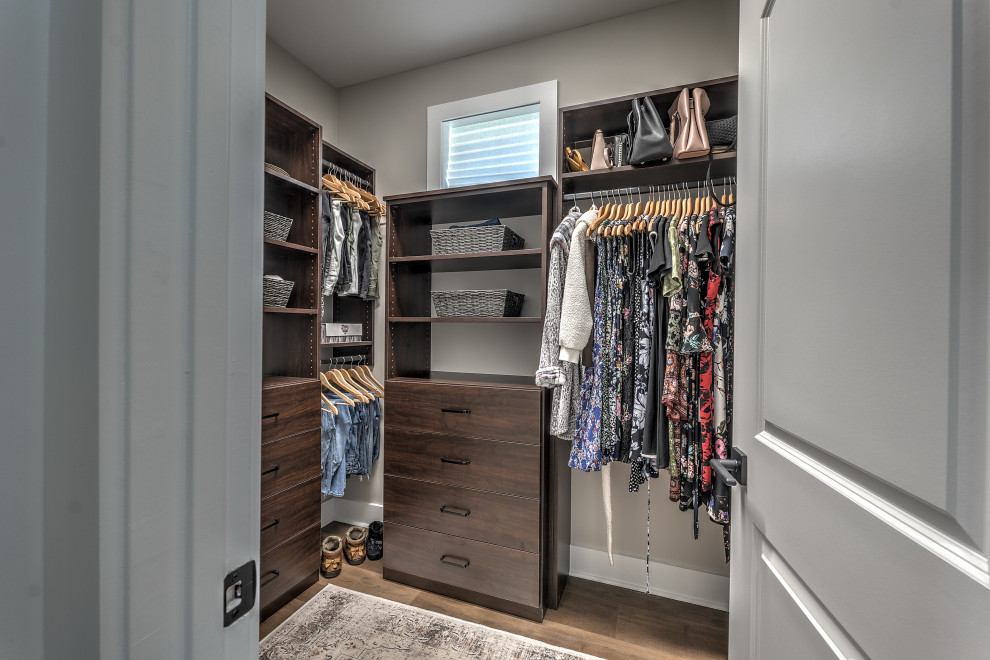 Mid-sized arts and crafts women's storage and wardrobe in Atlanta with flat-panel cabinets, dark wood cabinets, laminate floors and brown floor.