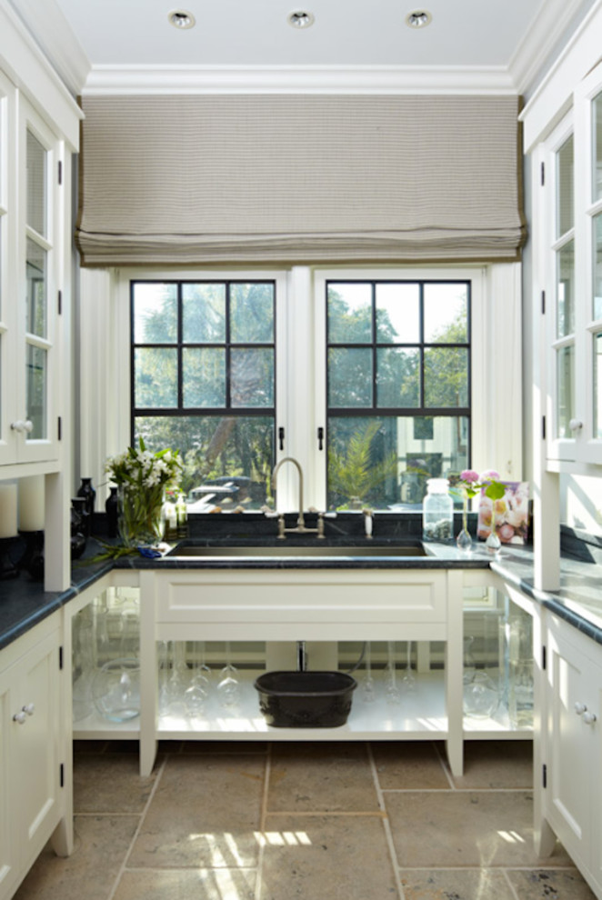 Photo of a mid-sized galley utility room in Charleston with an undermount sink, glass-front cabinets, white cabinets, marble benchtops, white walls and ceramic floors.