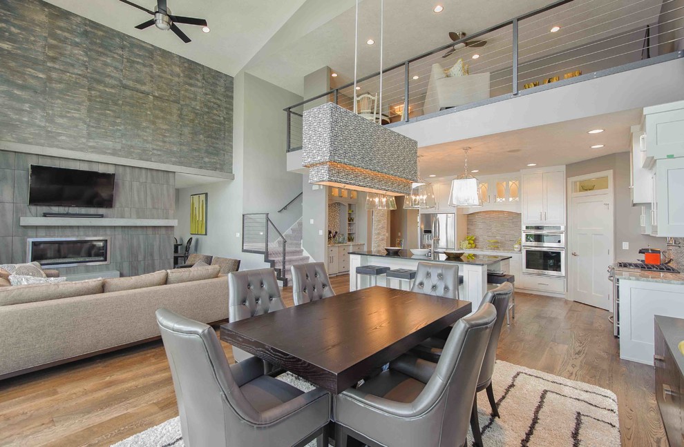 Large contemporary open plan dining in Other with grey walls, medium hardwood floors, a tile fireplace surround and a standard fireplace.