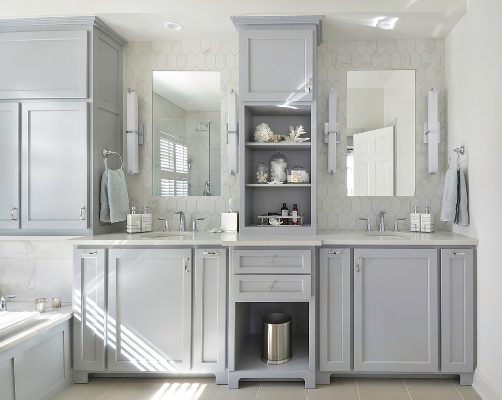Inspiration for a mid-sized transitional master bathroom in Atlanta with an undermount sink, recessed-panel cabinets, grey cabinets, engineered quartz benchtops, a drop-in tub, white tile, porcelain tile, white walls and porcelain floors.