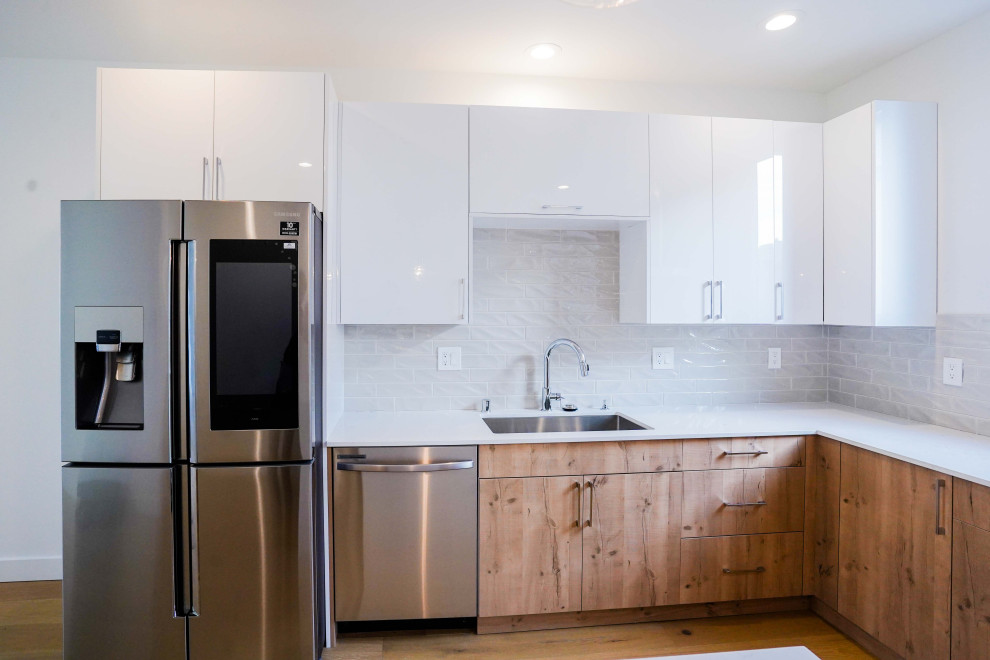 Photo of a large modern u-shaped kitchen/diner in Seattle with a submerged sink, open cabinets, white cabinets, quartz worktops, grey splashback, ceramic splashback, stainless steel appliances, medium hardwood flooring, an island, brown floors, white worktops and a wallpapered ceiling.