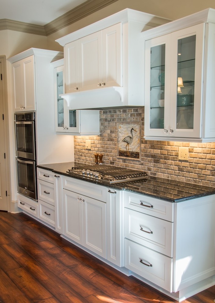 Design ideas for a large country u-shaped open plan kitchen in Raleigh with a farmhouse sink, flat-panel cabinets, white cabinets, marble benchtops, beige splashback, mosaic tile splashback, stainless steel appliances, medium hardwood floors and multiple islands.