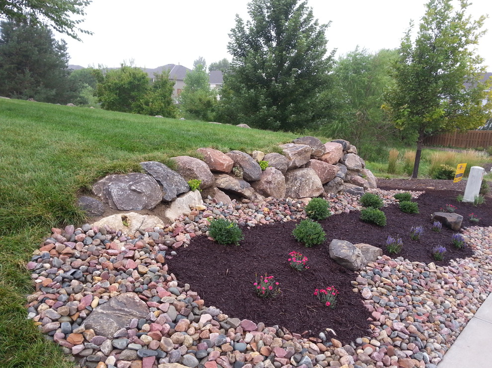 Small traditional sloped garden in Omaha with a retaining wall and mulch.