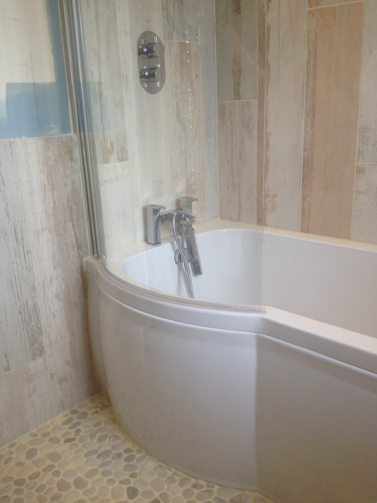 Photo of a mid-sized beach style bathroom in Cardiff with a wall-mount sink, a curbless shower, a one-piece toilet, pebble tile and pebble tile floors.