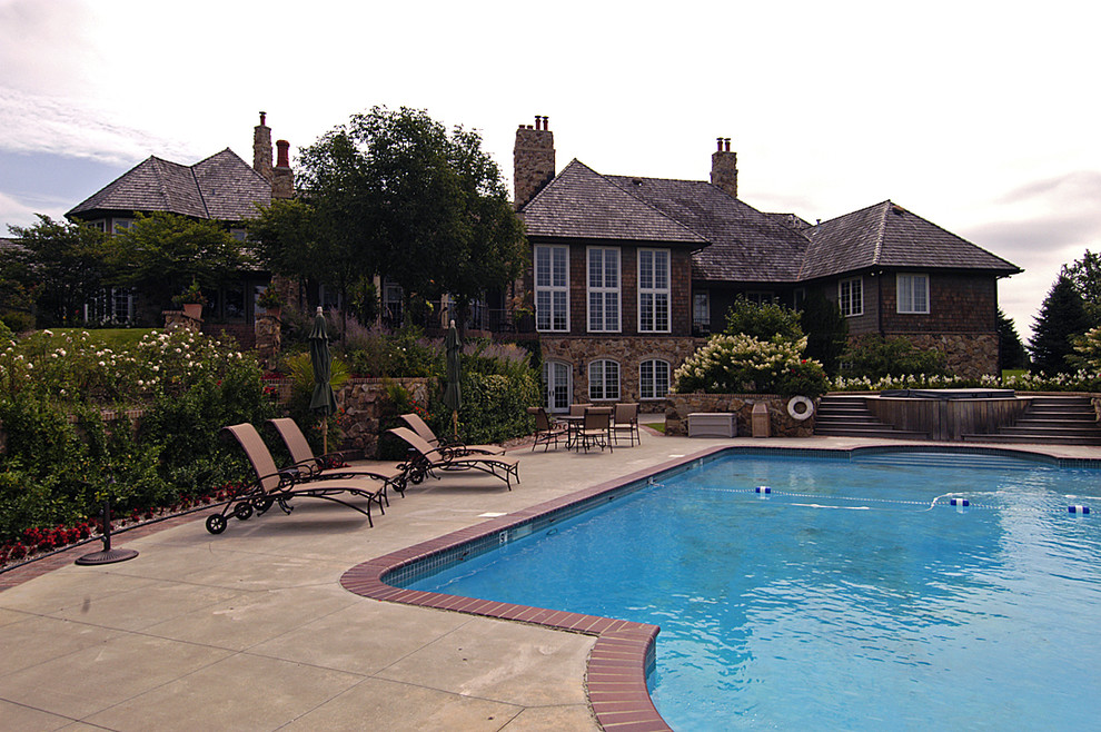 Photo of an expansive country backyard custom-shaped lap pool in Omaha with brick pavers.