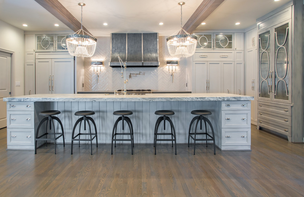 Design ideas for an expansive eclectic u-shaped eat-in kitchen in Houston with a farmhouse sink, glass-front cabinets, white cabinets, white splashback, porcelain splashback, stainless steel appliances, with island, marble benchtops and light hardwood floors.
