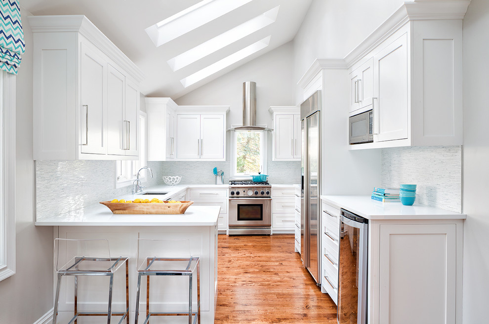 Inspiration for an u-shaped medium tone wood floor kitchen remodel in New York with an undermount sink, shaker cabinets, white cabinets, stainless steel appliances and a peninsula