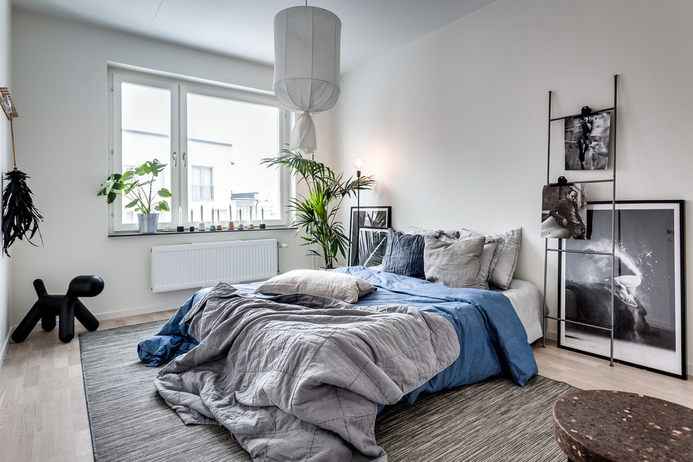 This is an example of a mid-sized scandinavian bedroom in Stockholm with grey walls and light hardwood floors.