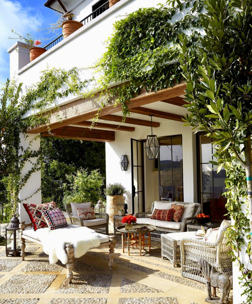 Foto di un patio o portico mediterraneo di medie dimensioni e dietro casa con pavimentazioni in pietra naturale e un tetto a sbalzo